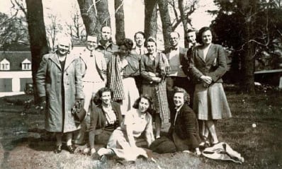 A group of people at Bletchley Park. Nine are stood up, with three sat down in front of them