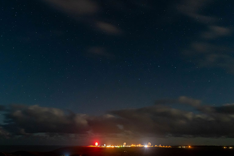 A panoramic shot of GCHQ's Bude station featuring a large satellite dish lit up in red to resemble a poppy.