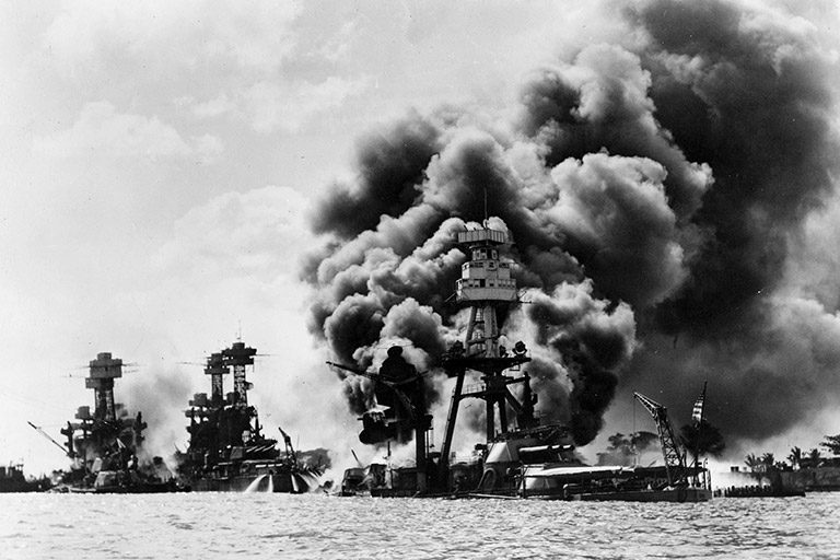 B&W photo of a stricken ship billowing black smoke