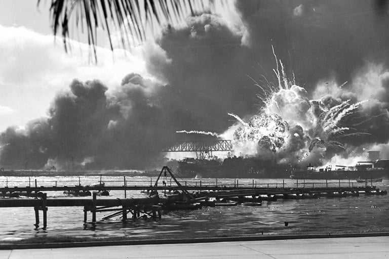 B&W photo showing a dramatic explosion of the ship; thick and fiery smoke clouds with projectiles