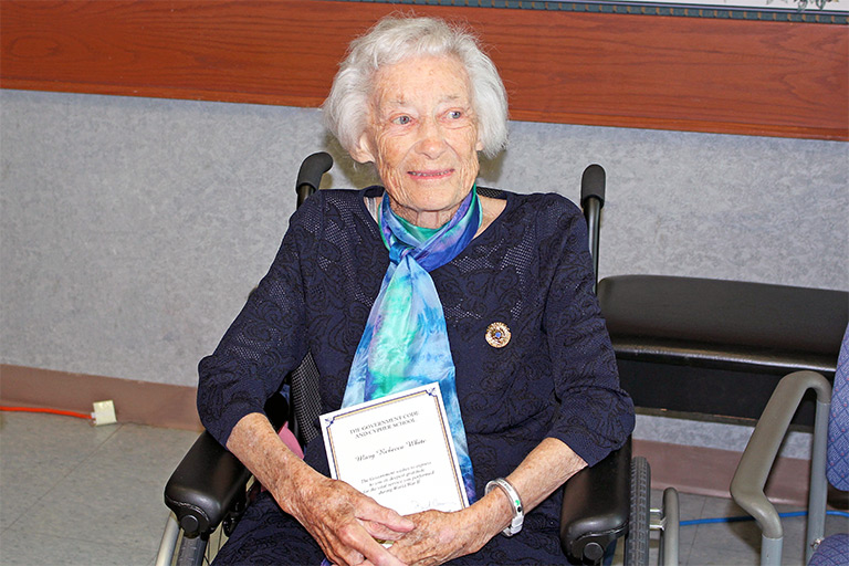 Becky wearing her Bletchley Park Commemorative Badge and holding her certificate signed by the UK Prime Minister