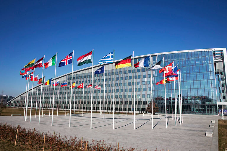 Huge building with all 28 NATO member's flags on a circle of flagpoles