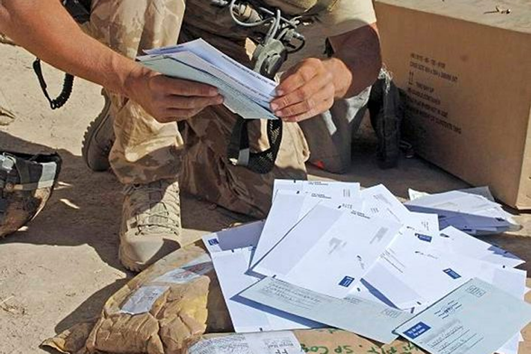 A soldier opens Festive mail at Camp Bastian