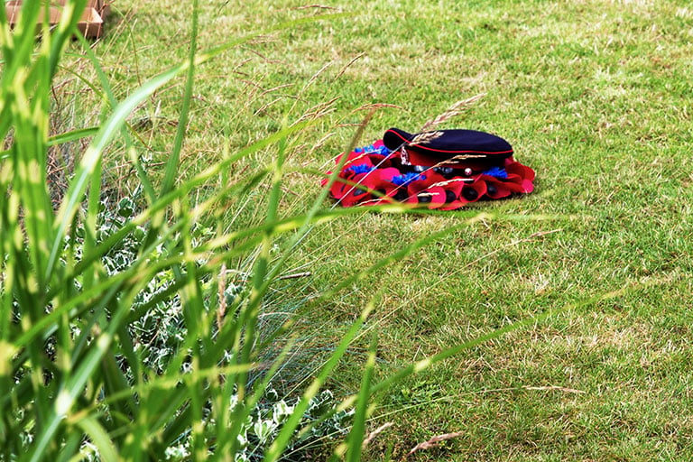 Poppy wreath and army cap carefully laid on the grass in the GCHQ courtyard garden