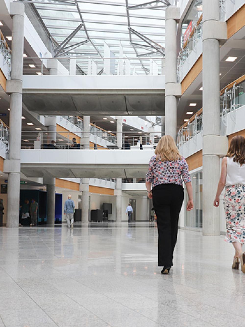 Two women, Emily and Vicky, with their backs to the camera, walking alongside each other inside GCHQ's headquarters