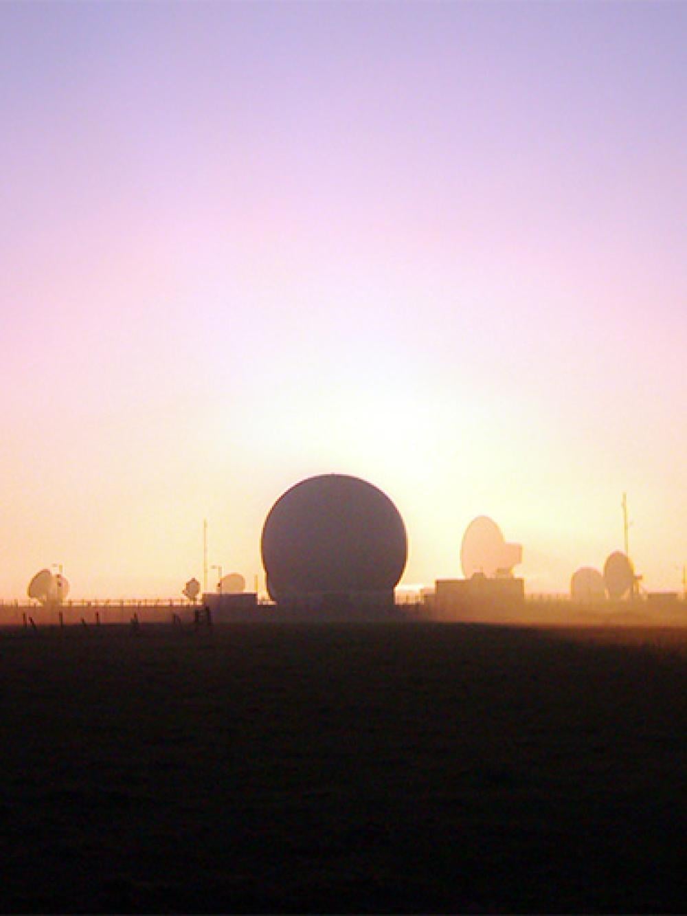 The sky shines oranges and pinks, silhouetting the satellite dishes