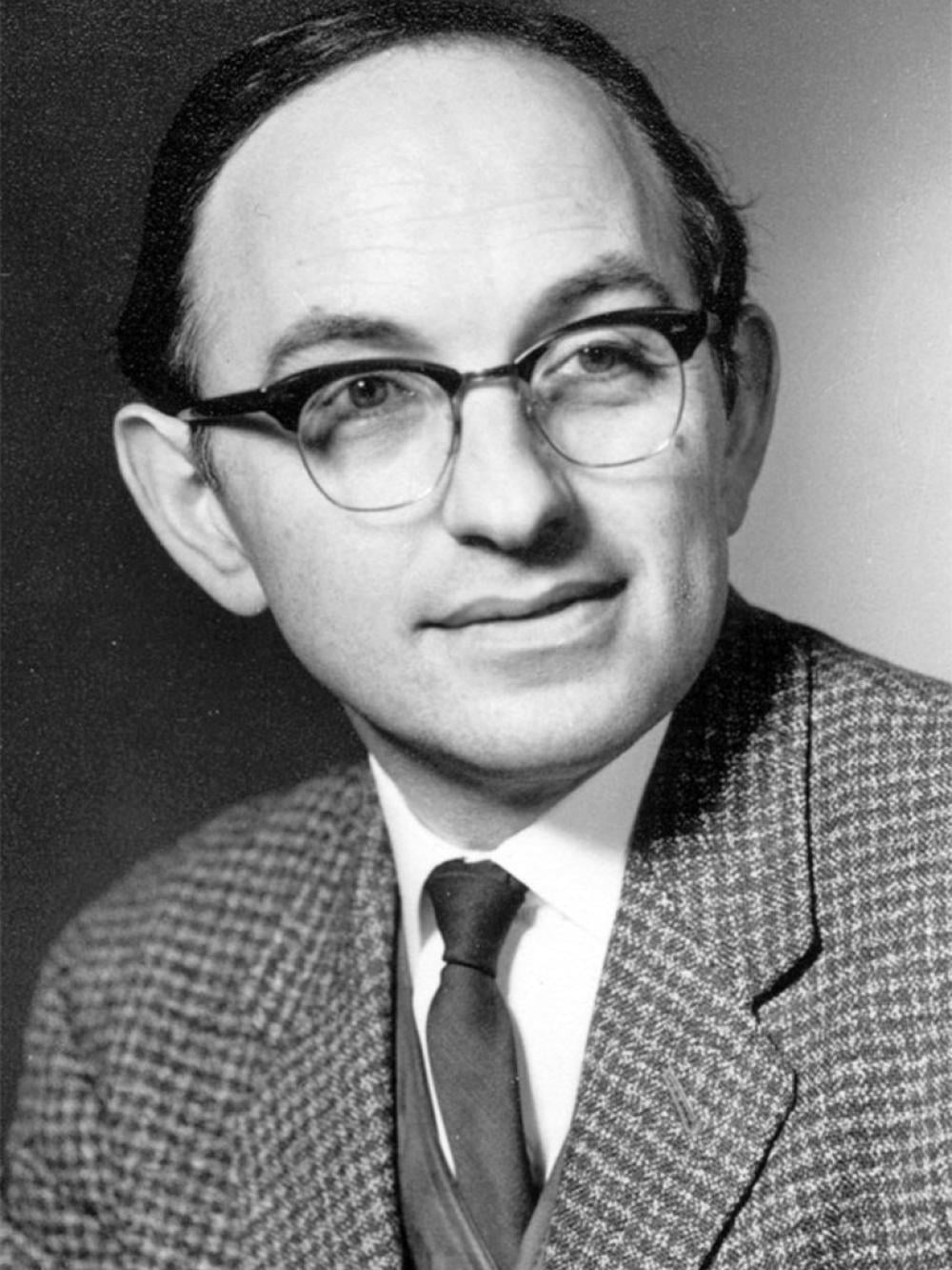 Black and white portrait photo of Jack Good, a white male, wearing glasses and suit.