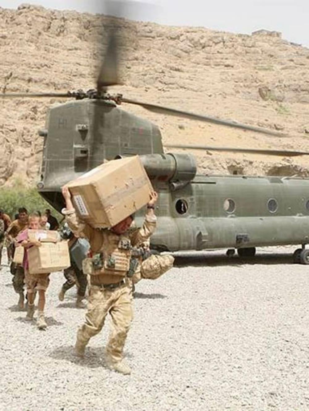 Servicemen carrying boxes from a military helicopter in Afghanistan