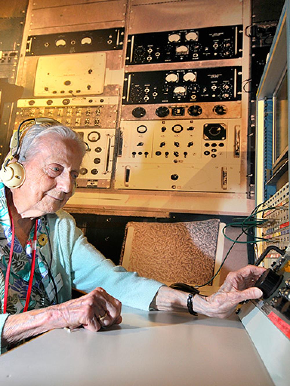Pamela Hussey MBE sat with headphones on at old signals intelligence equipment
