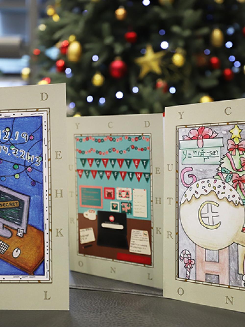 An image of a trio of Christmas Cards in the foreground. In the background is a Christmas tree.