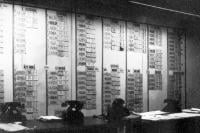 Wall covered with lists of countries, cities, and numbers, with old-fashioned telephones on a table
