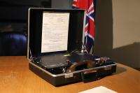 The Brahms secure portable telephone housed within an open briefcase on a desk with the Union Jack in the background