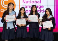 The winners of the National Language Competition pose with their trophy and certificate in front of a screen with logo