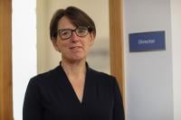 An image of GCHQ Director Anne Keast-Butler in front of a sign on a door that reads 'Director'