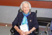 Becky wearing her Bletchley Park Commemorative Badge and holding her certificate signed by the UK Prime Minister