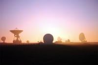 The sky shines oranges and pinks, silhouetting the satellite dishes