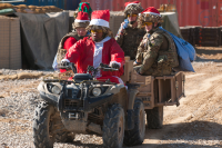 A number of soldiers with two in Father Christmas outfits on quad bikes at Camp Bastian