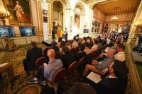 Image of attendees of the Cyber Accelerator sat watching a presentation in a grand room