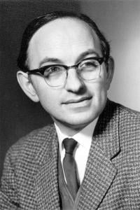 Black and white portrait photo of Jack Good, a white male, wearing glasses and suit.