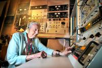 Pamela Hussey MBE sat with headphones on at old signals intelligence equipment